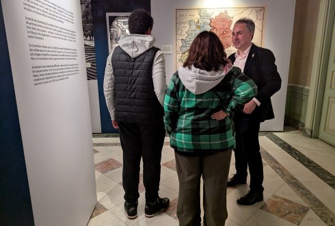 Un commissaire explique l'exposition à un couple de personnes